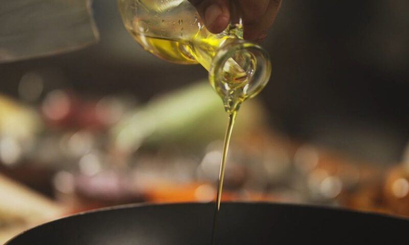 osoba sipa maslinovo ulje u tiganj