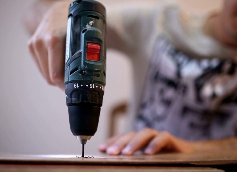 muškarac buši rupu sa bušilicom