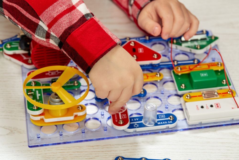 Dete sastavlja električno kolo pomoću edukativnog kompleta za eksperimente.